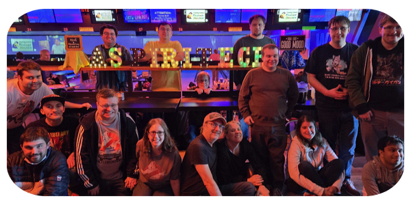 Aspiritech team members smile in a group photo at a bowling alley.